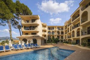 a resort with a swimming pool and chairs and a building at Apartamentos Casa Vida in Santa Ponsa