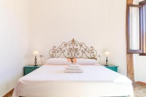 a bedroom with a white bed with a metal headboard at Casa Ombrina in Orosei