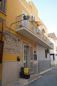 a yellow building with a balcony and a door at Happy Home in Pozzallo