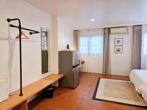 a bedroom with a bed and a desk and a refrigerator at Baan Rak BTS phromphong Emsphere in Bangkok