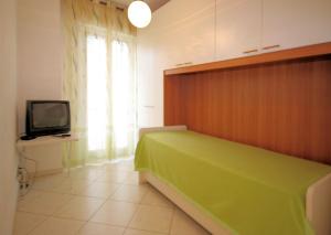 ロアーノにあるTRILOCALE Manatthan LOANOの緑色のベッドとテレビが備わる客室です。