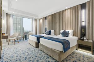 two beds in a hotel room with a large window at Taj Dubai in Dubai