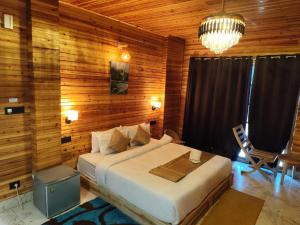 a bedroom with a bed and a wooden wall at Pradhan Hotel Mirik Lake Side in Mirik