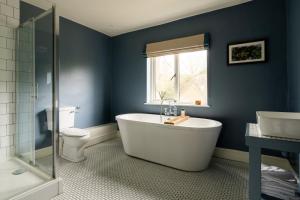a bathroom with a tub and a toilet and a window at Bel and The Dragon-Cookham in Cookham