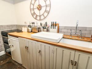 a kitchen with a sink and a clock on the wall at Englewood Cottage in Hexham +30 photos