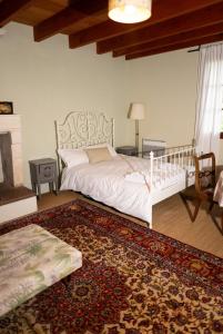 a bedroom with a white bed and a rug at Longère de charme en pleine nature in Chillac