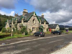 a large stone house with cars parked in front of it at The Tomich Hotel in Inverness