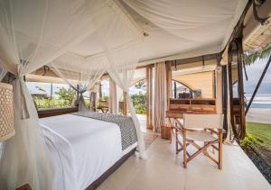 a bedroom with a bed and a desk in a room at Bali Beach Glamping in Tabanan