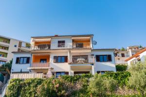 an apartment building with balconies on a hill at Apartmani Zlata in Rabac