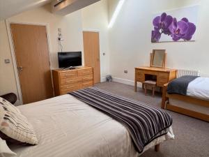 a bedroom with a bed and a desk with a television at The Shelbourne in Southport +146 photos