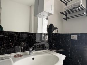 a bathroom with a white sink and a black wall at Cozy Apartments and Rooms in Caselle di Sommacampagna +45 photos