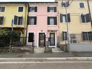 a pink house with black shutters on a street at Cozy Apartments and Rooms in Caselle di Sommacampagna