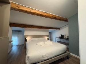 a bedroom with a large white bed with wooden beams at Cozy Apartments and Rooms in Caselle di Sommacampagna