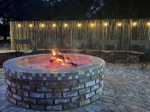 a brick fire pit with chairs and a wooden fence at Moyo Safari Lodge in Alldays