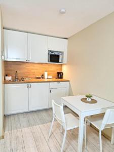 a kitchen with white cabinets and a table and chairs at Dunes Trail 4 in Melnragė