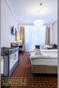 a hotel room with three beds and a desk at Hotel Podium in Wisła