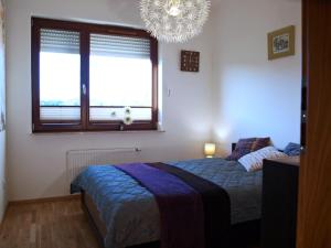 - une chambre avec un lit, une fenêtre et un lustre dans l'établissement Apartament Aga Świnoujście, à Świnoujście