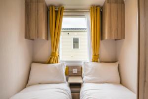 two beds in a small room with yellow curtains at Beverley Park in Goodrington +18 photos