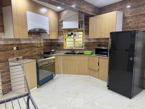 a kitchen with wooden cabinets and a black refrigerator at Home away from Home in Komé