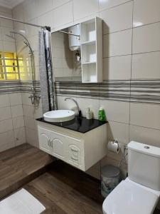 a bathroom with a sink and a toilet and a mirror at Home away from Home in Komé
