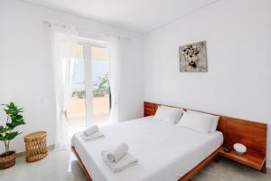 a white bedroom with a bed and a large window at CorfuLevante Sea View in Barbati