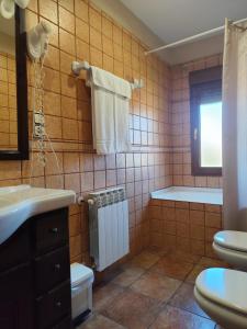 a bathroom with a sink and a toilet and a tub at Raco del Tosca in Beceite