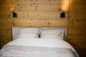 uma cama com duas almofadas brancas e uma parede de madeira em La Chabane em Chamonix-Mont-Blanc