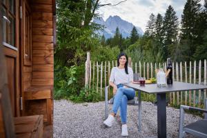 a woman sitting at a table with a bottle of wine at Alpen-Schlaffass in Grainau