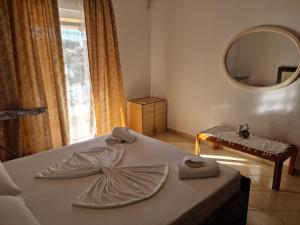 a bedroom with a bed with towels and a mirror at Alban Apartament in Lukovë