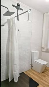 a bathroom with a toilet and a shower curtain at Casa Tía Maruja in Rianjo +8 photos