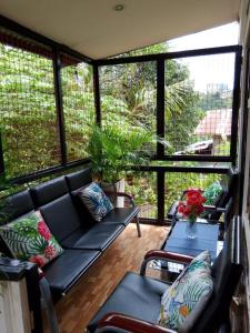 a screened in porch with a black couch and chairs at Laguerta Tahas House in Cebu City