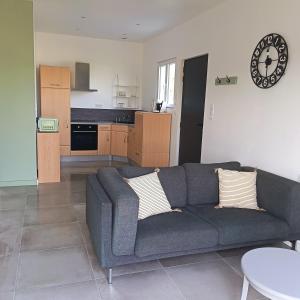 a living room with a couch and a kitchen at Logement 1 - proche Le Mans in Aigné