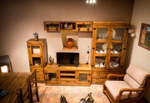 una sala de estar con un centro de entretenimiento de madera con TV en Casa Rural el Meson, en Fermoselle