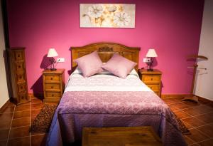 a bedroom with a bed with pink walls and two night stands at Casa Rural el Meson in Fermoselle
