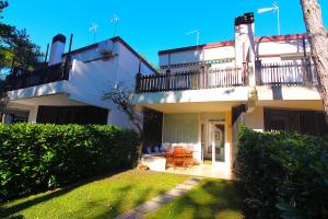 a white house with a balcony and a patio at Villaggio Estate in Lignano Sabbiadoro