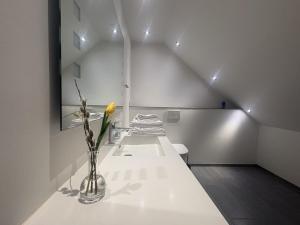 a white room with a vase with a yellow flower in it at Tollundgaard Golf Park & Apartments in Funder Kirkeby +39 photos