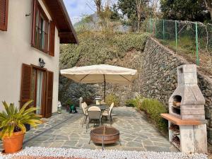a patio with an umbrella and a table and chairs at Terrazza fra lago e monti in Gravedona