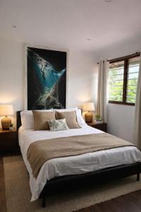 a bedroom with a large bed with a painting on the wall at KAZ DIBWA Beach House in Glacis