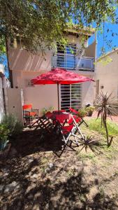 a red table and chairs under a red umbrella at La Mar in Mar de Ajó