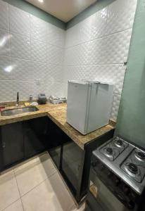 a kitchen with a refrigerator and a stove in it at kit net master simple in Divinópolis