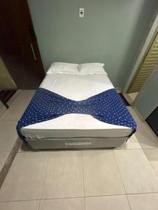 a bed with a blue polka dot sheet on it at kit net master simple in Divinópolis +2 photos