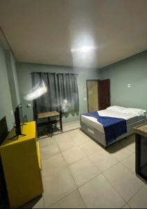 a bedroom with a bed and a table and a chair at kit net master simple in Divinópolis