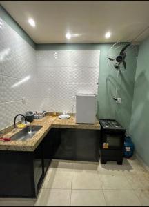 a kitchen with a counter and a sink and a fan at kit net master simple in Divinópolis