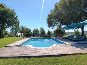 a swimming pool with a deck and chairs and an umbrella at Escale Zen en Quercy in Montalzat +5 photos