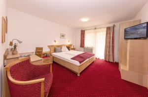 a hotel room with a bed and a desk and a television at Pension Mayerhofer in Piesendorf