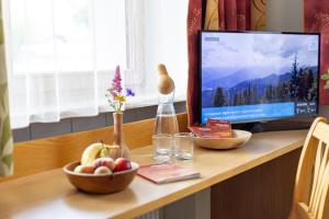 a desk with a television and a bowl of fruit at Pension Mayerhofer in Piesendorf +9 photos