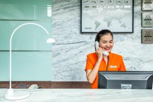 Hotel Solo, Sukhumvit 2, Bangkok - SHA Extra Plus في بانكوك: امرأة تتحدث على الهاتف أمام جهاز كمبيوتر