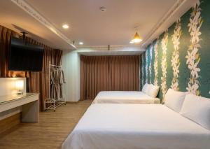 a hotel room with two beds and a flat screen tv at Ezstay Station in Kaohsiung