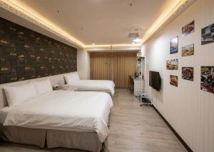 a hotel room with two beds and a television at Ezstay Station in Kaohsiung