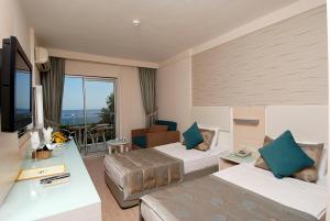 a hotel room with two beds and a television at Grand Okan Hotel in Alanya